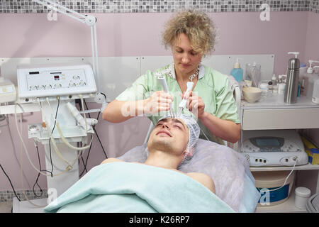 Menschen, die sich einer microcurrent Gesichtsbehandlung. Kaukasische Kerl in der kosmetologie Klinik. Stockfoto