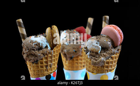 Gourmet Schokolade-Eis mit Makronen Beeren und Früchte auf einem schwarzen Hintergrund dekoriert. Stockfoto