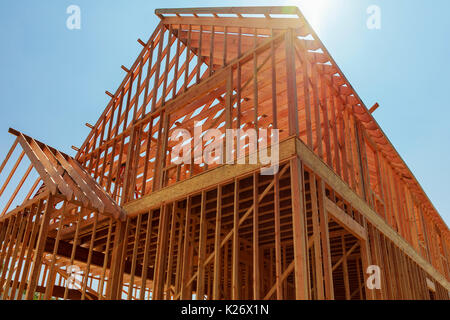 Ein Einfamilienhaus im Bau. Das Haus wurde hintergangen und in Sperrholz abgedeckt. Stapel von Bord Holz vor und Stapel von 2x4-Boards auf Stockfoto