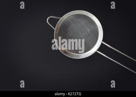 Küche tools Sieb Mehl oder Zucker filter Draufsicht auf schwarzem Hintergrund Stockfoto