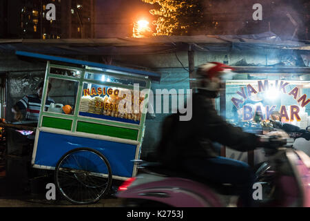 Mann, einen Roller auf einer Straße mit Ständen in einem armen Dist Stockfoto