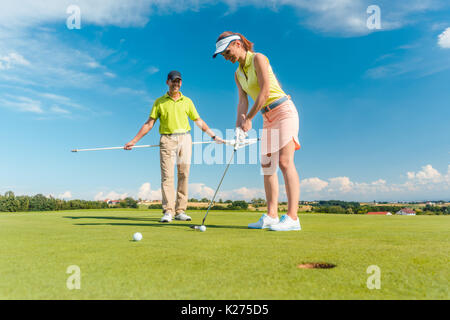 Die volle Länge einer Frau spielen professionelles Golf mit ihren männlichen m Stockfoto