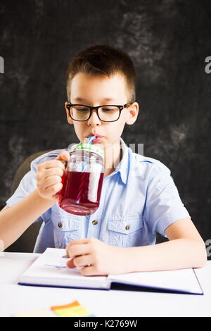 Junge Saft trinken beim Schlichten Hausaufgaben zu Hause Stockfoto