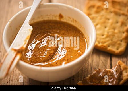 Almond Butter in Schüssel mit Crackern auf hölzernen Tisch Stockfoto