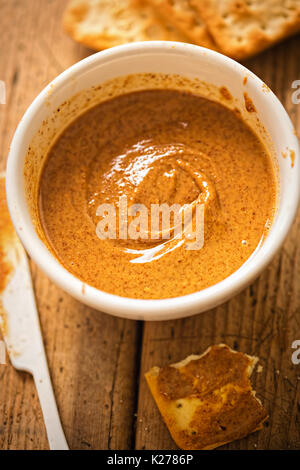 Almond Butter in Schüssel mit Crackern auf hölzernen Tisch Stockfoto