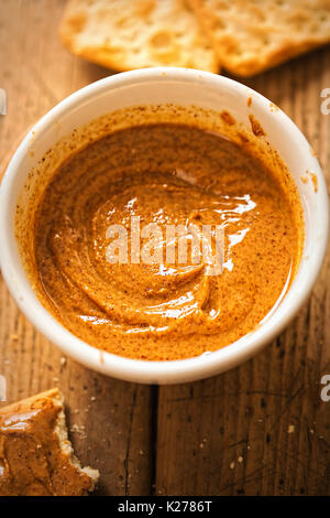 Almond Butter in Schüssel mit Crackern auf hölzernen Tisch Stockfoto