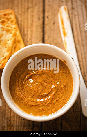 Almond Butter in Schüssel mit Crackern auf hölzernen Tisch Stockfoto