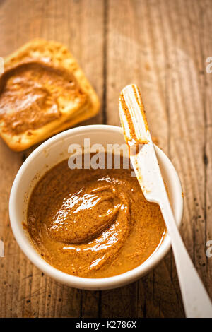 Almond Butter in Schüssel mit Crackern auf hölzernen Tisch Stockfoto