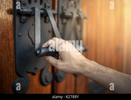 Die Hand eines Mannes klopft an eine große Kirche Tür. Stockfoto