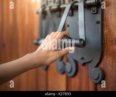 Frauen Hand Klopfen auf eine große Kirche Tür. Stockfoto