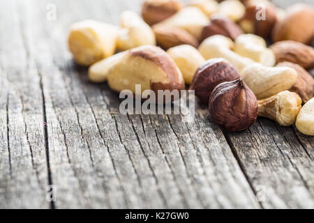 Verschiedene Arten von Nüssen. Haselnüsse, Walnüsse, Mandeln, Paranüsse, Pistazien auf alten Holztisch. Stockfoto