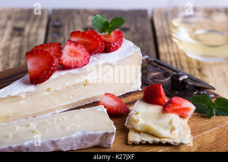 Käseplatte. Brie mit frischen Erdbeeren und Minze auf rustikalen Holzbrett Stockfoto