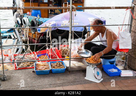 Hongkong - Juli 13, 2017: ein Fischer verkauft getrocknete Meeresfrüchte an der Pier am Sai Kung Floating Seafood Market in Hong Kong. Stockfoto