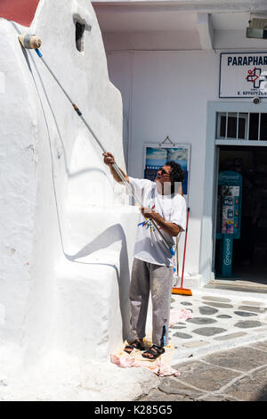 Ein Mann besetzt Übertünchen eine Kirche an der Wand, Mykonos, Griechenland. Stockfoto