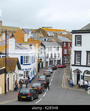 Staus, bei der die Zeile der Autos an der roten Ampel in der schmalen Straße zwischen hohen Gebäuden in Lyme Regis, Dorset, England Stockfoto