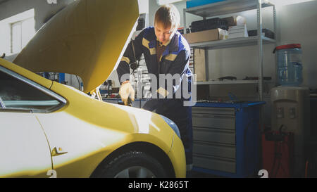 Adac-Mechaniker schraubt Detail des Autos in der Motorhaube, Slider Stockfoto