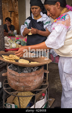 Juni 25, 2017 Cotacachi, Ecuador: Quechua Frauen Vorbereitung flatbreds von Mais bei Inti Raymi Fest, die auf der Seite der Straße. Stockfoto