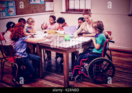 Hübsche Lehrer helfen Schülern im Klassenzimmer Stockfoto