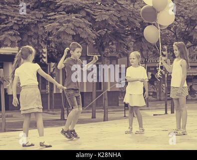 Gruppe der glückliche Kinder zusammen mit Skipping Seilspringen auf städtischen Spielplatz Stockfoto