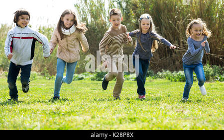 Aufgeregt Kinder voller Energie im Rennen durch das Feld ausführen Stockfoto