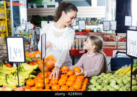 Lächelnde junge Frau und kleines Mädchen kaufen Obst im Supermarkt Schnell-Restaurant Stockfoto