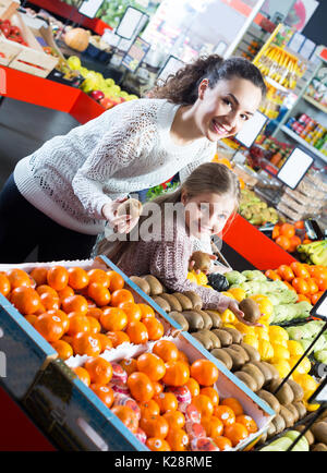 Junge Frau und Tochter Einkauf Früchte und lächelnd in Store Stockfoto