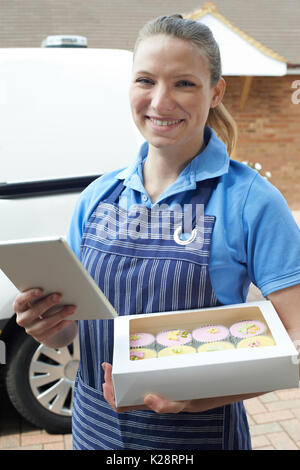 Weibliche Baker mit digitalen Tablet, Home Delivery von Cupcakes Stockfoto