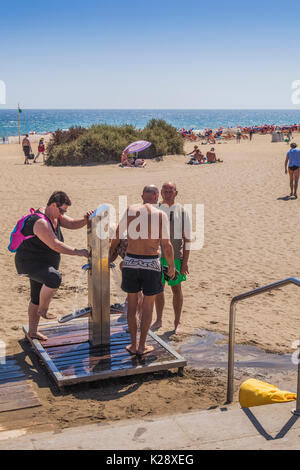 Die Leute am Strand Waschen aus der Sand in Playa del Ingles auf Gran Canaria. Playa Ingles ist der Ort, wo Stockfoto