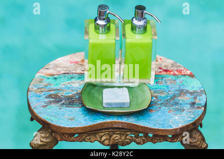 Zwei Flaschen Shampoo und handgemachte Seife auf alte kleine Vintage lackiert Tisch in der Nähe von privaten Luxus Pool. Dusche und Wellness-Set im Hotel Stockfoto