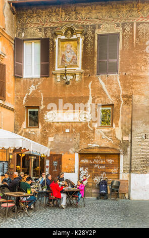 Touristen und Römer zu Mittag vor der historischen Fassade im historischen Stadtzentrum Roms. Stockfoto