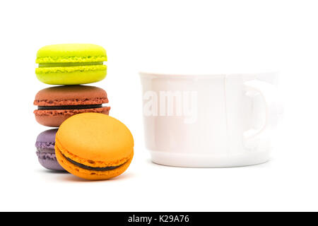 Turm von süßen Macarons und eine heiße Tasse Tee auf weißem Hintergrund Stockfoto