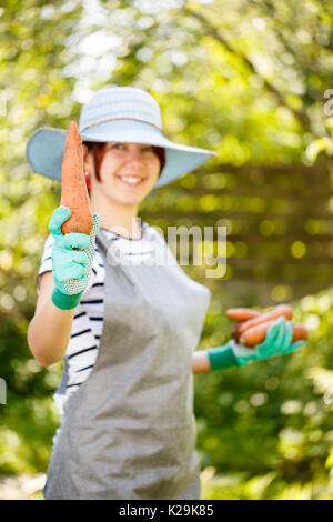 Mädchen in Handschuhe hält Karotte Stockfoto