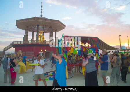 Brenner sammeln sich um die Burning Man Statue bei Sonnenuntergang auf der Playa als jährliche Desert Festival Burning Man am ersten Tag der Woche schließt, bei der 27. August 2017 in Black Rock City, Nevada. Das jährliche Festival lockt 70.000 Teilnehmer in einer der entlegensten und unwirtlichen Wüsten in Amerika. Stockfoto