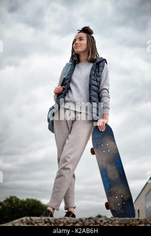 Schöne hipster Mädchen mit Skate Board stehend mit Lächeln Stockfoto