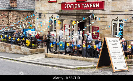 Besucher mit einem Getränk vor dem Bahnhof Taverne bei Grosmont Stockfoto