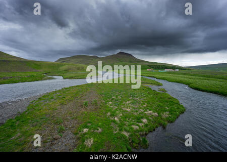 Island - Natürliche Flusslauf durch grüne Felder und unberührte Landschaft Stockfoto