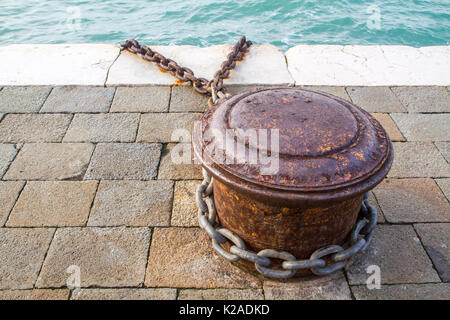 Rostige Poller und Metall Kette links im Hafen in Venedig, Italien Stockfoto