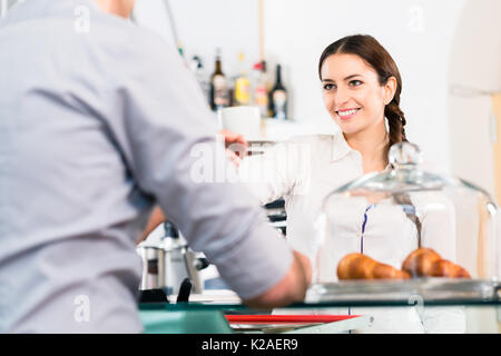 Schöne Kellnerin mit männlichen Kunden mit einer Tasse Kaffee fo Stockfoto