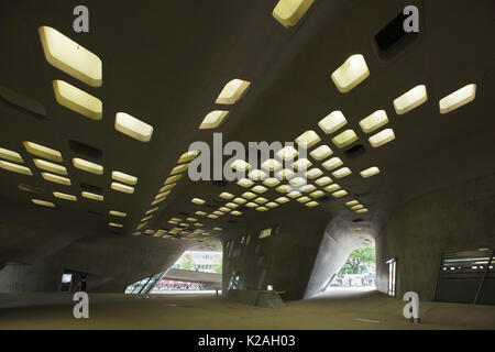 Menschen laufen unter dem Wissenschaftszentrum Phaeno von Irakischen konzipiert - geborene britische Architektin Zaha Hadid in Wolfsburg, Niedersachsen, Deutschland. Stockfoto