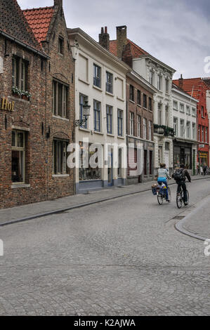 Ein paar Zyklus in einer ruhigen Straße mit Kopfsteinpflaster in der mittelalterlichen Stadt Brügge/Brügge, Westflandern, Belgien Stockfoto