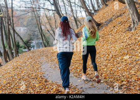 Blond und afrikanischen Mädchen Jogging im Herbst Park. Gelbe Blätter. Stockfoto