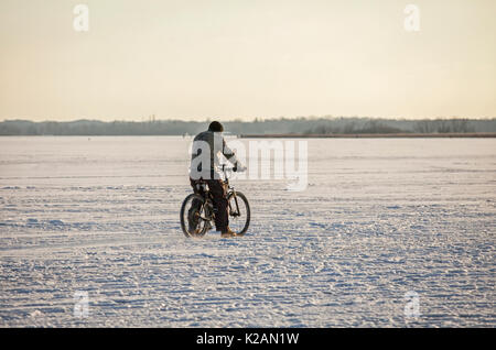 Die NIEDERLANDE - FEB 9: Mann, Radfahren über einen zugefrorenen See am Feb 9, 2012. In diesem Februar Temperaturen in den Niederlanden zu einem außergewöhnlich niedrigen gesunken Stockfoto