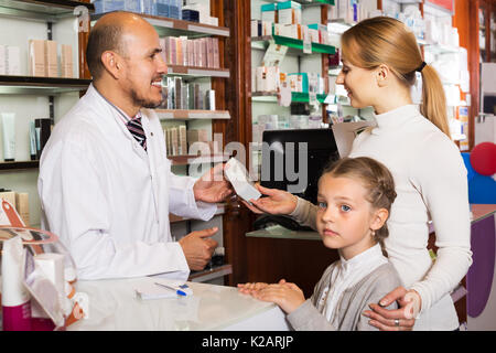 Positive reife Apotheker mit einer Kasse in der Apotheke und Kunden helfen Stockfoto