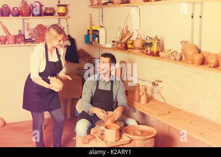 Freundliche Handwerker, Topf mit Keramik Rad und im Gespräch mit Frau Kollegin in der Keramik Werkstatt Stockfoto