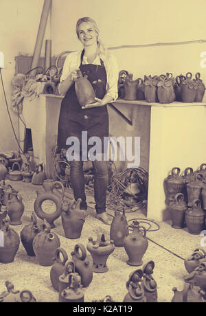 Portrait von fröhlichen weibliche Handwerker mit Schwarz verglaste Keramik Vasen im Atelier Stockfoto