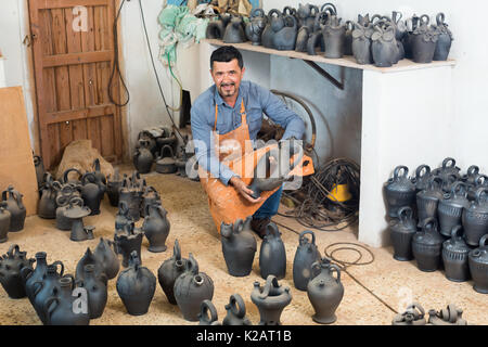 Portrait von fröhlichen männlichen Artisan mit Schwarz verglaste Keramik Vasen im Atelier Stockfoto