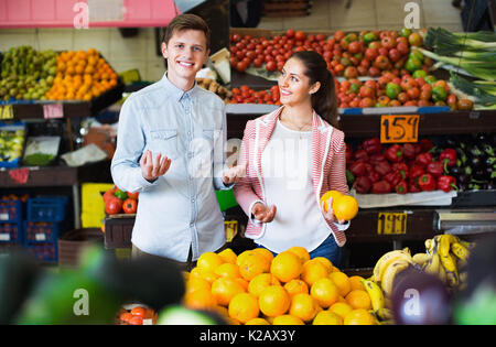 Junge schöne Mädchen und lächelnden Freund kaufen Zitrusgewächse in Lebensmittelgeschäft Stockfoto