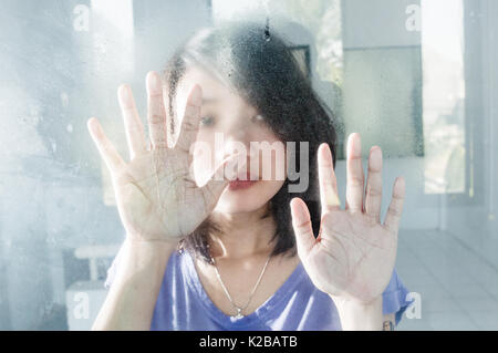 Traurige Frauen hinter einem Fenster Stockfoto