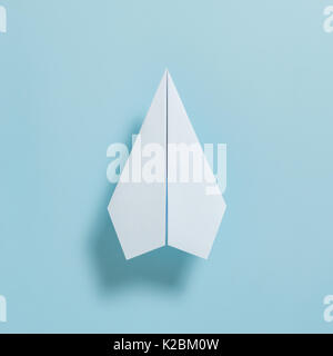 Flach von White Paper Plane auf Pastell-blaue Farbe Hintergrund Stockfoto