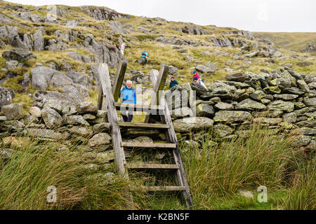 Leiter Stil über trockenmauern Wand mit Wanderer auf Fußweg hinunter Pen Jahr Ole Wen. Ogwen Valley, Conwy, North Wales, UK, Großbritannien Stockfoto